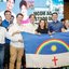 Raquel Lyra, Simão Durando, Ministro das Comunicações, Miguel Coelho e outras pessoas. Eles seguram uma bandeira de Pernambuco enquanto sorriem