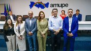 Em frente à logo da Amupe Pedro Freitas, Douglas Nóbrega, três mulheres brancas e um homem branco calvo