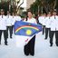 Raquel Lyra segura bandeira ao lado de diversos homens com roupas brancas e quepes