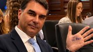 Flávio Bolsonaro em reunião nos EUA. Mão de Flávio Bolsonaro com escrita "PT Tax Party", que significa PT, partido das taxas