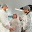 Zilda Cavalcanti e Renato Cirne com toucas e aventais médicos conversam com homem de touca, avental e máscara. Ao fundo, área com teto quebrado e equipamentos médicos