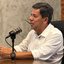 Mendonça Filho fala em microfone de Podcast sentado em cadeira
