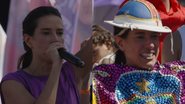 Raquel Lyra fala ao microfone, ao lado foto de Raquel Lyra com chapeu de couro com estampa de pernambuco e manto de maracatu