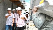 Victor Marques, Felipe Cury e outros homens usam capacete de obras em área de construção