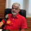 Humberto Costa sentado em frente a um microfone.