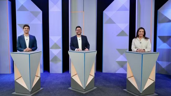 Cada um em um púlpito separado, João Campos, Ivan Moraes e Raquel Lyra sorriem em pé lado a lado