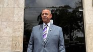 Luiz Rocha olha para frente de terno e olha em frente à sede da Polícia Federal