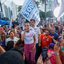 Raquel Lyra fala em microfone ao redor de multidão. Eduardo da Fonte está atrás dela. Todos em pé. Ao redor bandeiras