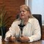 Andrea Medeiros fala sentada em frente a microfone de podcast