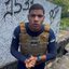 Imagem mostra Emerson Freitas com colete policial e camisa de manga comprida preta, numa escadaria