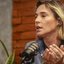 Foto mostra a ex-vice prefeita Isabella de Roldão, no estúdio do podcast, com camisa cinza. Ela é branca, tem cabelos claros e curtos. Está falando ao microfone e gesticulando com as mãos