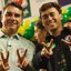 Flávio Bolsonaro e Nikolas Ferreira sorriem fazendo o símbolo de 2 e 2 com as mãos