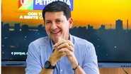 Imagem mostra prefeito de Petrolina com camisa social azul clara, sentado, e com as mãos juntas próximas ao queixo, sorrindo