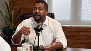 Vini Castello fala em microfone de podcast
