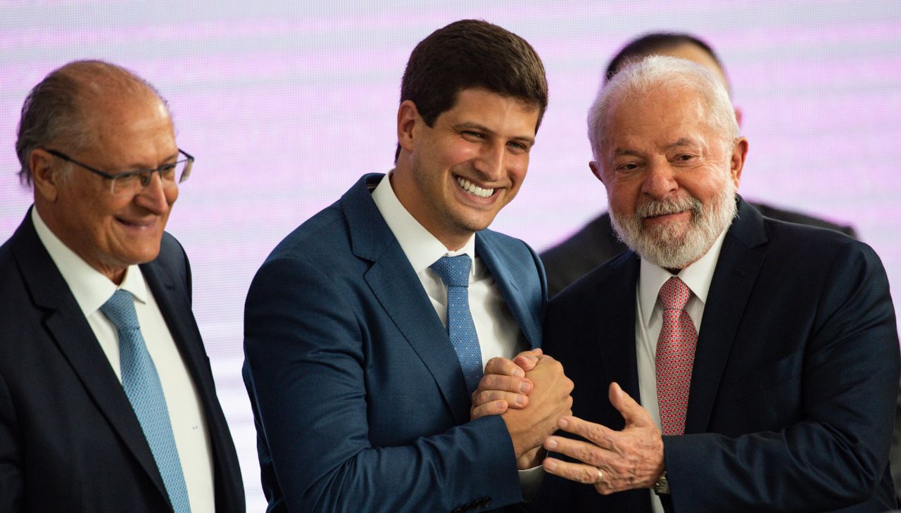O prefeito João Campos aperta a mão do presidente Lula enquanto sorriem, ao lado está o vice-presidente Geraldo Alckmin