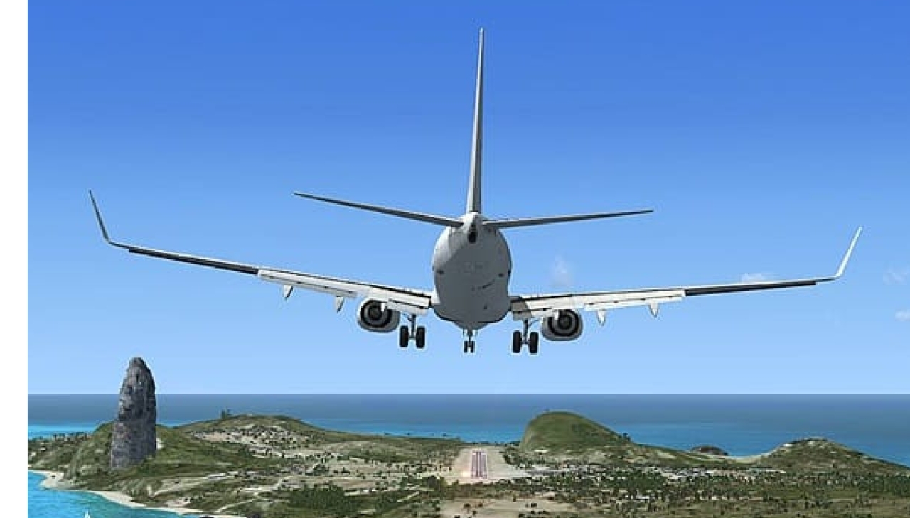 Foto de um avião decolando, é possível ver o céu, o mar, e uma parte da vegetação de um local