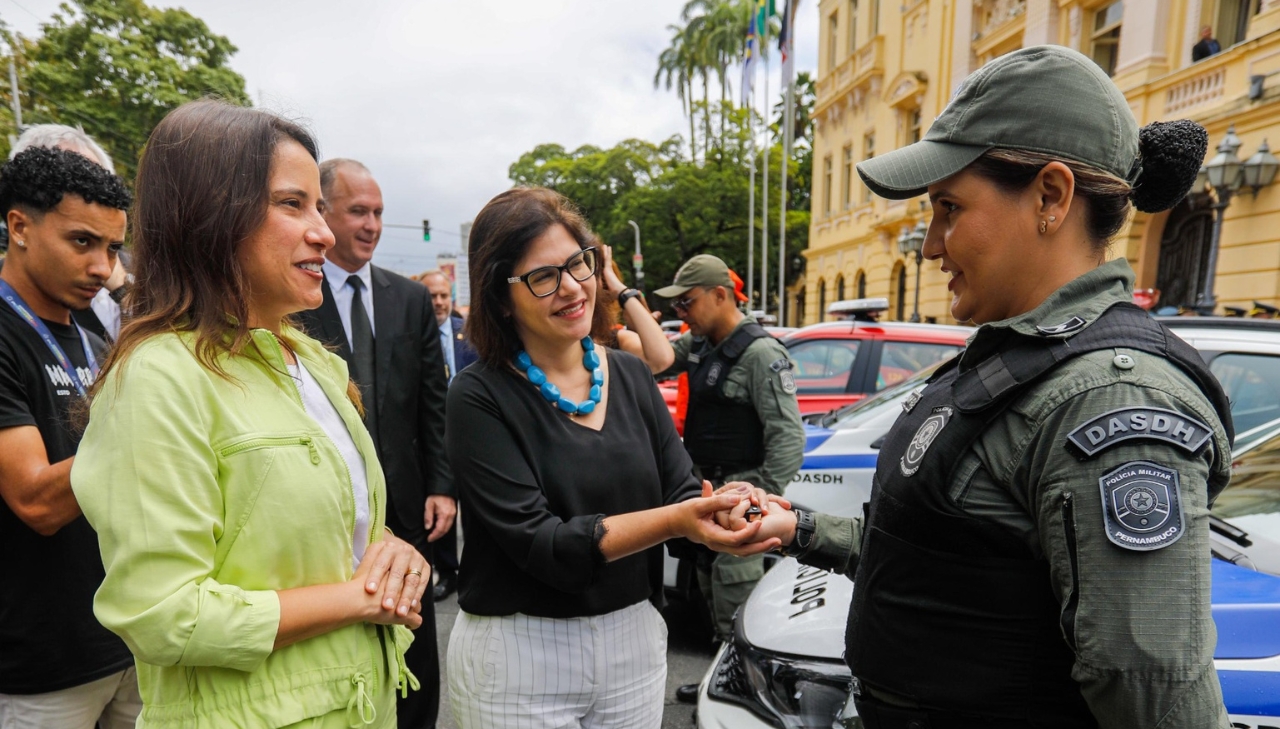 Foto de Raquel Lyra e Priscila Krause na rua conversando com uma policial fardada