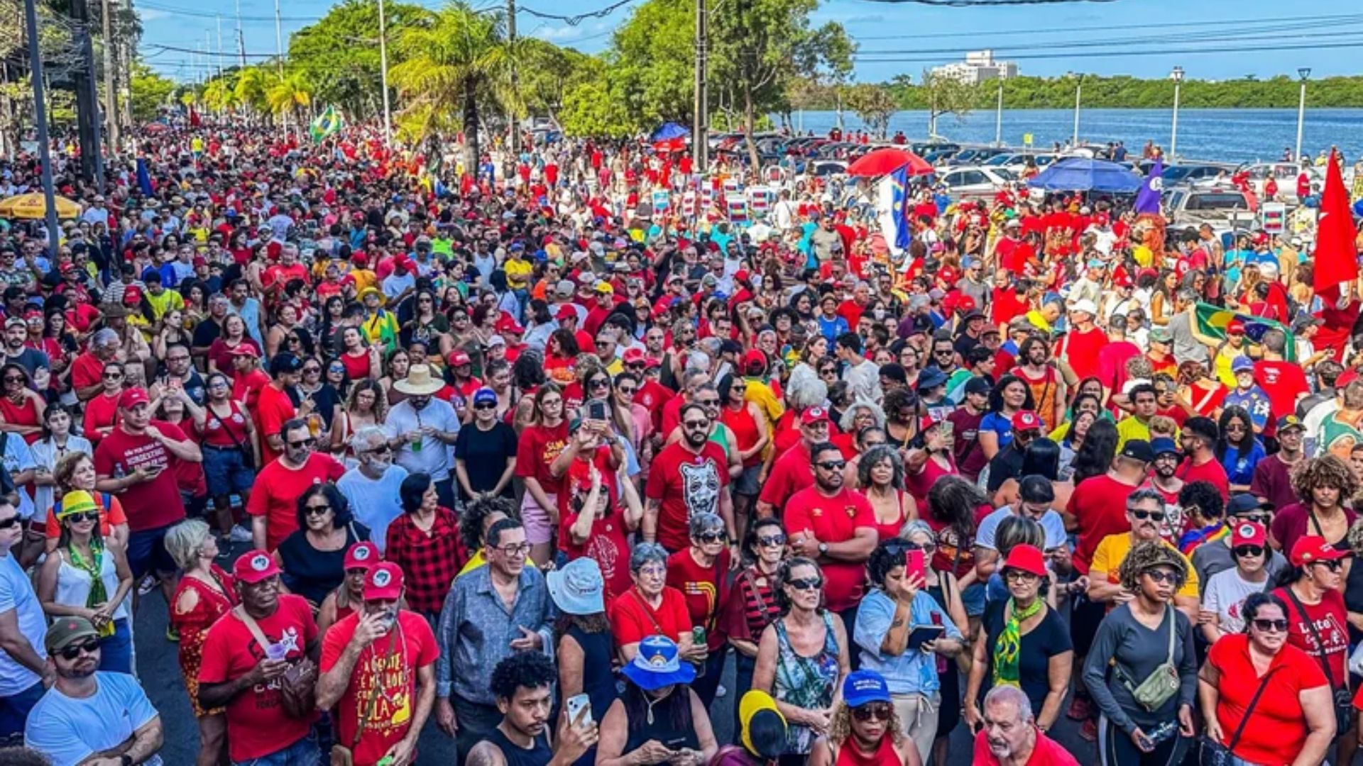 Multidão de pessoas, maioria usa vermelho ou roupas com as cores do Brasil, estão em uma ponte