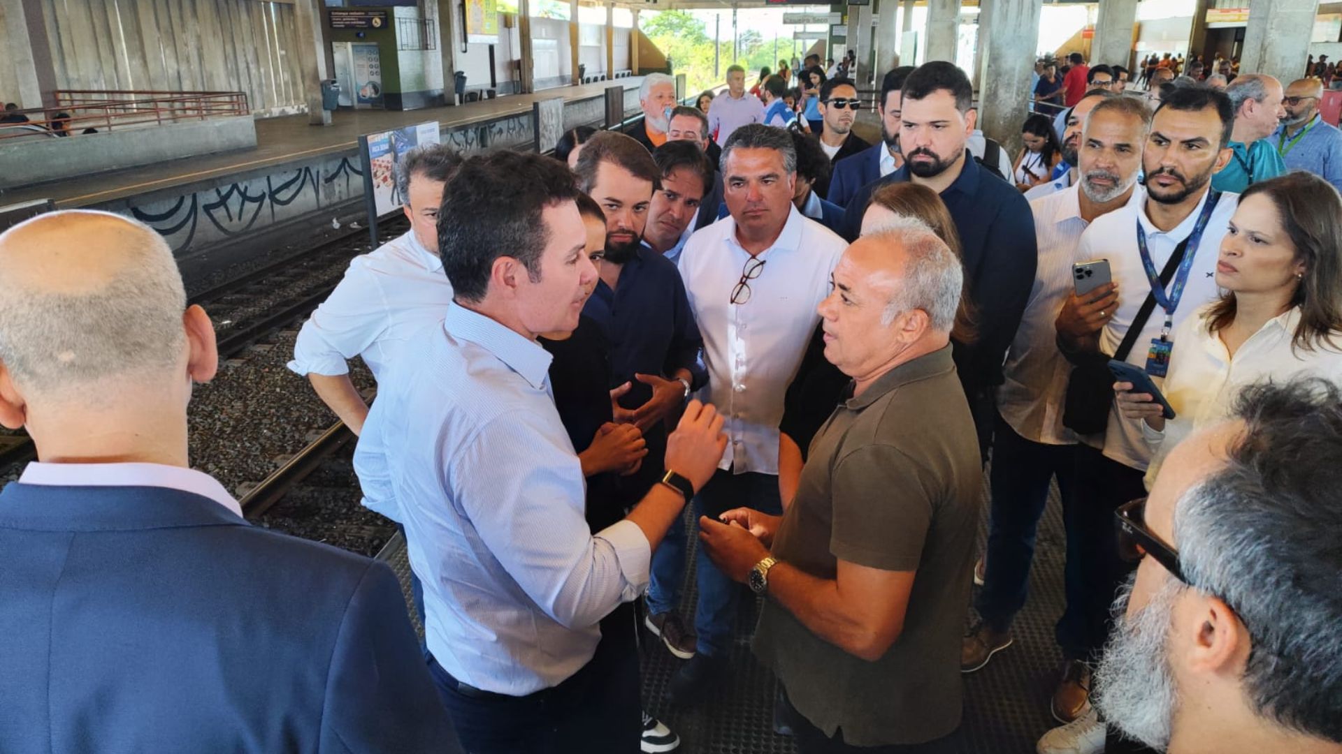 Com multidão ao redor, Raquel Lyra e Jader Filho falam com Luiz Soares. Ao fundo estrutura do Metrô Recife