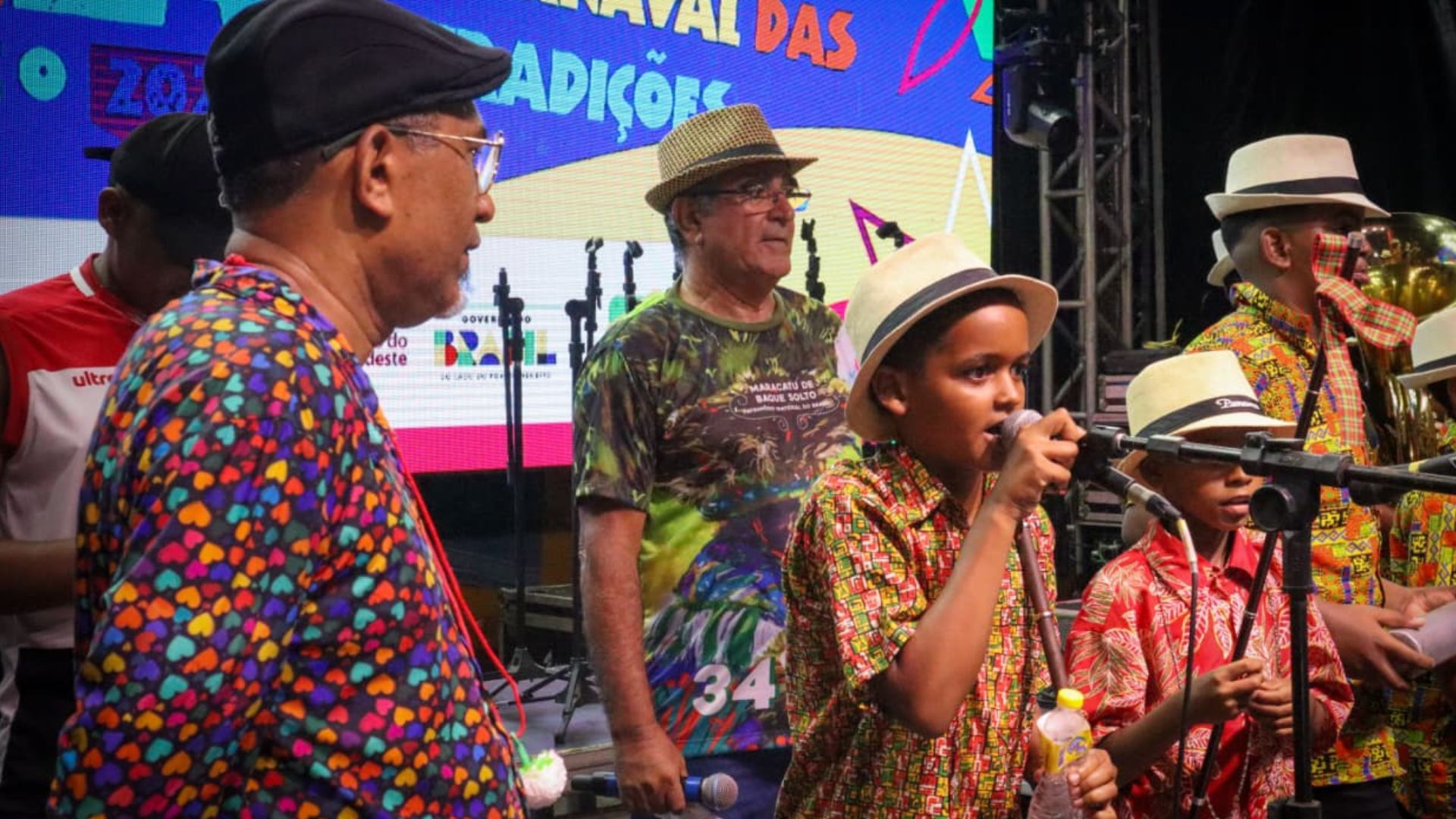 Maciel Salu no palco com grupo de brincantes mirins.