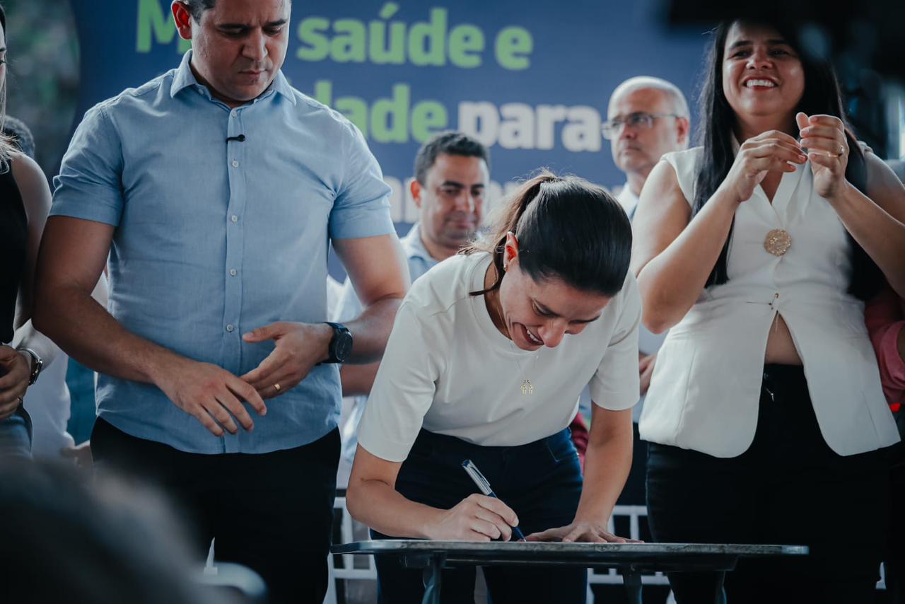 Raquel Lyra assinando papel