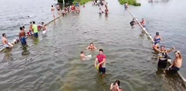 Pessoas brincam em Ponte do Cumbe alagada