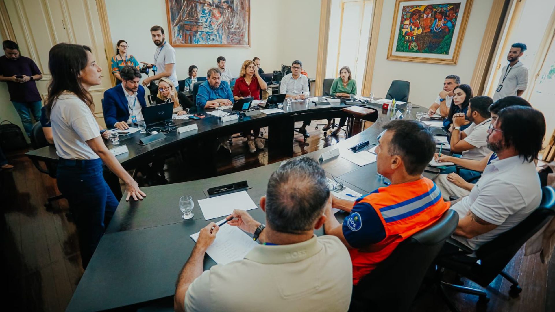 Raquel Lyra em frente à equipe do Governo de Pernambuco em reunião. Raquel em pé, restante sentado em mesa de reunião ao seu redor