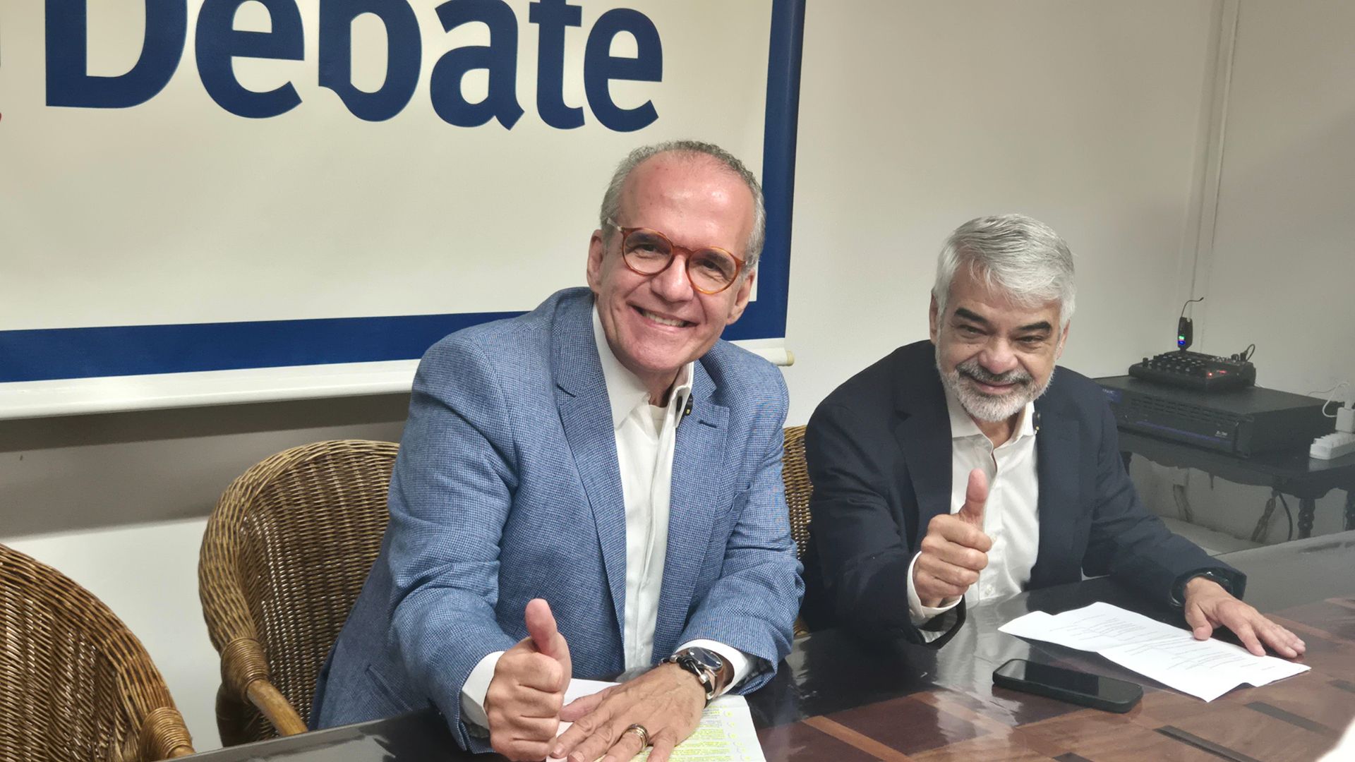 Humberto Costa e Fernando Dueire sentados fazem um joinha enquanto sorriem